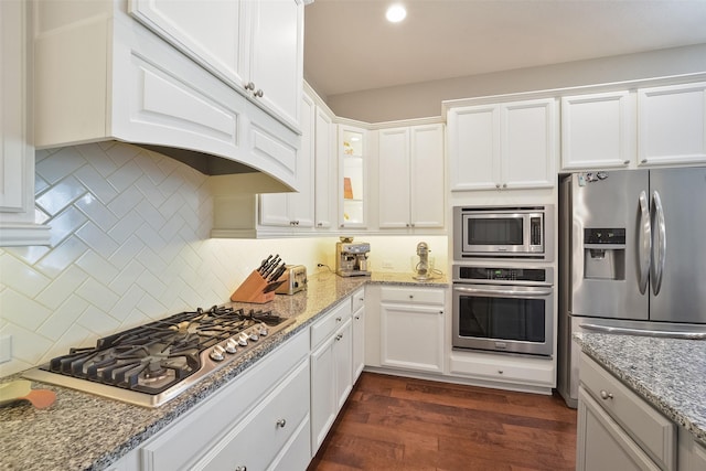 kitchen with tasteful backsplash, dark wood-style floors, glass insert cabinets, stainless steel appliances, and white cabinetry