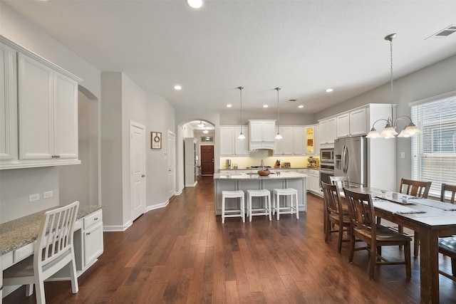 dining room with visible vents, arched walkways, dark wood-type flooring, and recessed lighting