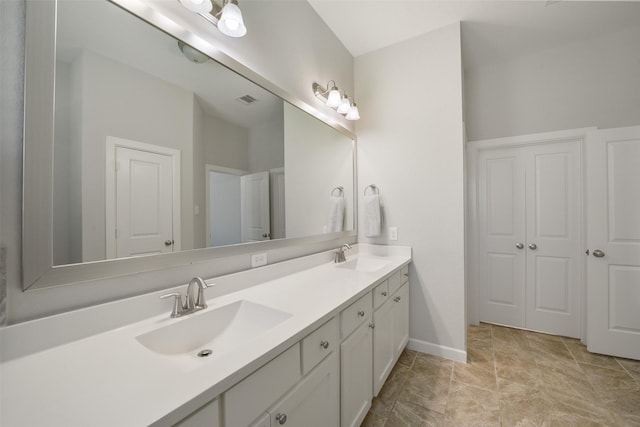 bathroom with visible vents, a sink, baseboards, and double vanity