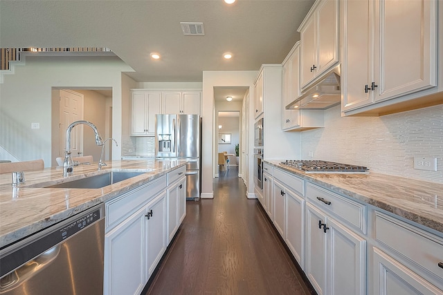 kitchen with visible vents, under cabinet range hood, a sink, white cabinetry, and appliances with stainless steel finishes