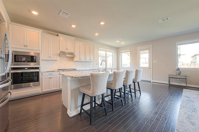 kitchen featuring under cabinet range hood, visible vents, white cabinets, and stainless steel appliances