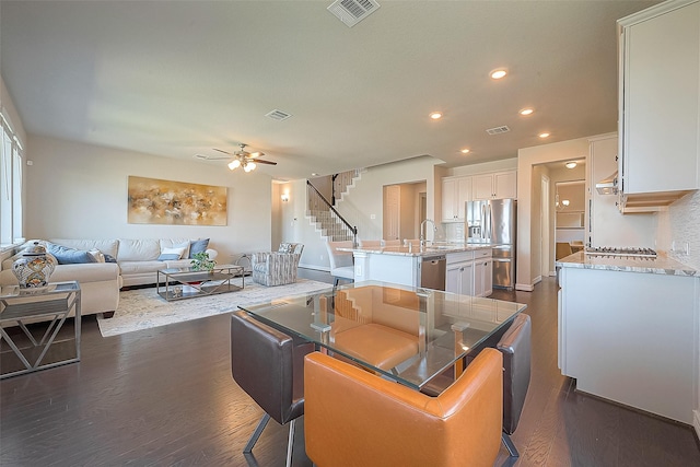 kitchen with visible vents, appliances with stainless steel finishes, dark wood-style flooring, and a kitchen island with sink