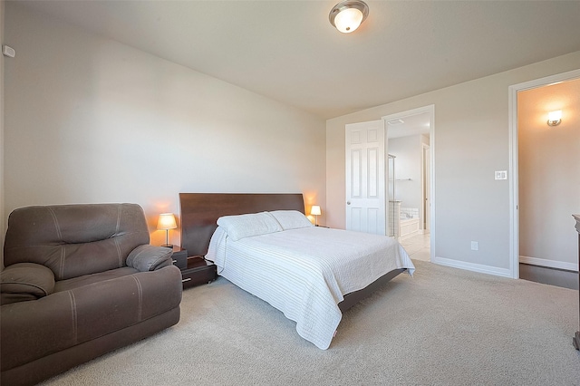 bedroom with baseboards, light carpet, and ensuite bath