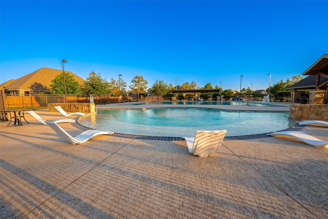 community pool with a patio area and fence