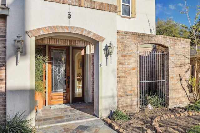 doorway to property with brick siding and stucco siding