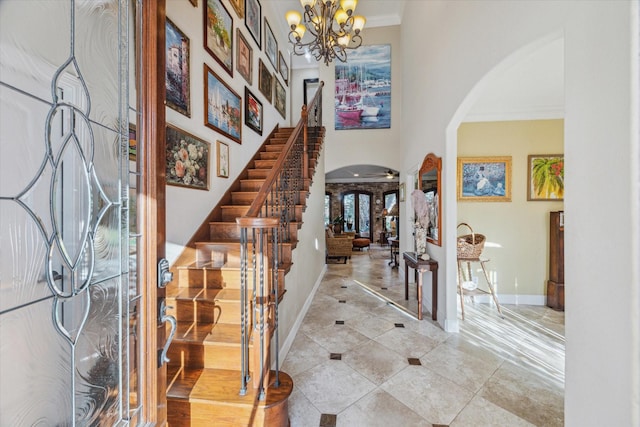 tiled foyer with arched walkways, ornamental molding, stairs, and a notable chandelier