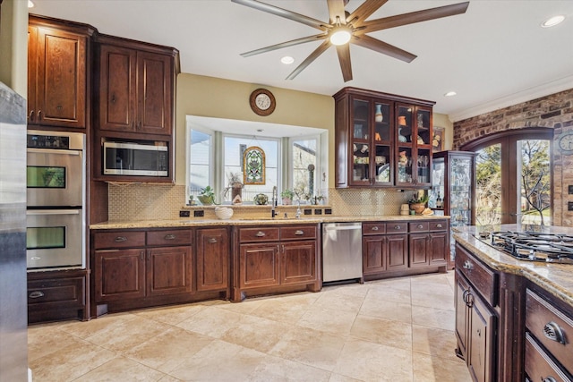 kitchen featuring stainless steel appliances, a sink, light stone counters, and tasteful backsplash