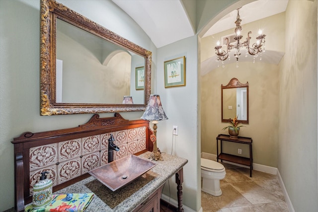 bathroom featuring lofted ceiling, toilet, a notable chandelier, vanity, and baseboards