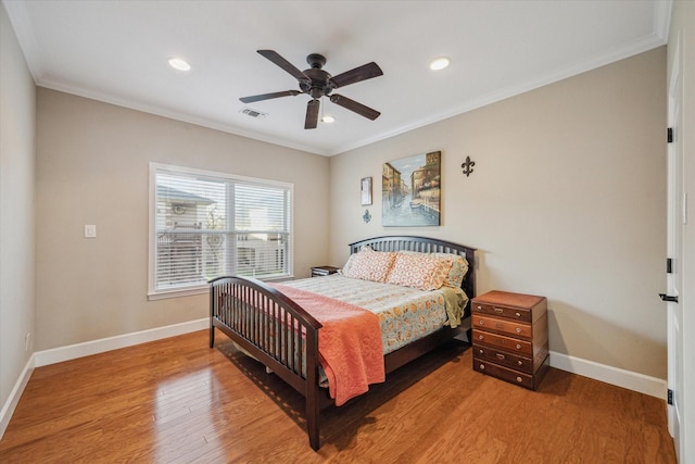 bedroom with visible vents, crown molding, baseboards, and wood finished floors