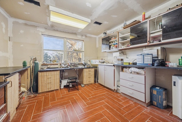 kitchen featuring dark countertops, visible vents, open shelves, and a sink