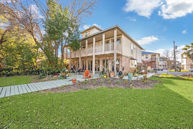 back of property featuring a lawn, a balcony, fence, a patio area, and brick siding