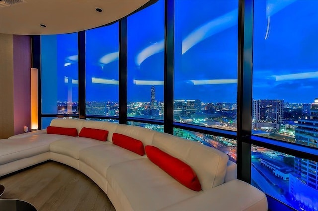 living room with a city view, floor to ceiling windows, and wood finished floors