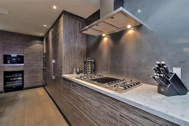 kitchen featuring visible vents, light wood-type flooring, light countertops, stainless steel gas stovetop, and wall chimney exhaust hood