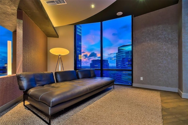 living area with a wall of windows, visible vents, baseboards, and wood finished floors