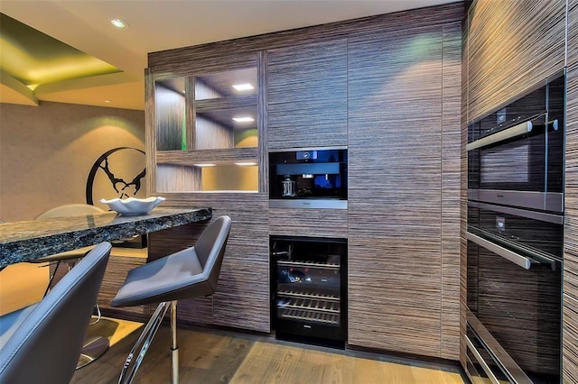 bar featuring wall oven, wood finished floors, and recessed lighting