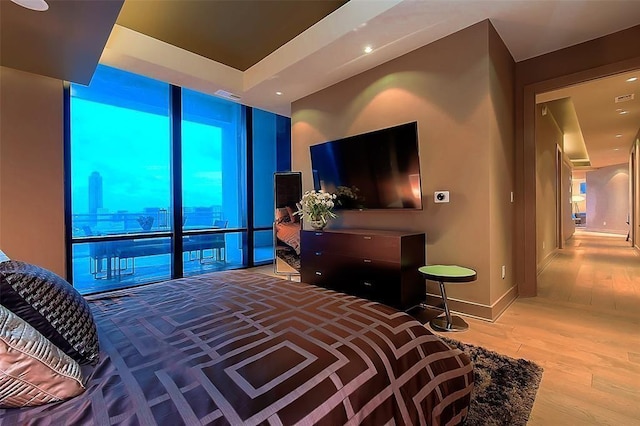 bedroom featuring expansive windows, baseboards, visible vents, and wood finished floors