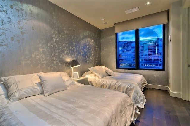 bedroom featuring wallpapered walls, wood finished floors, visible vents, and baseboards