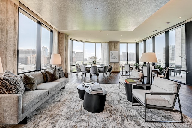 living area with visible vents, a wall of windows, wood finished floors, a view of city, and a textured ceiling