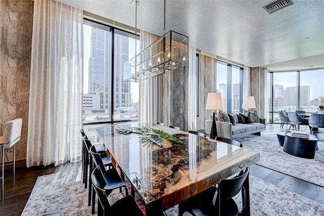 dining room featuring visible vents, dark wood-type flooring, a textured ceiling, floor to ceiling windows, and a chandelier