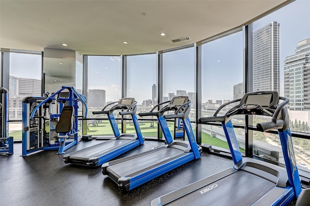 workout area with a wall of windows, a view of city, recessed lighting, and visible vents