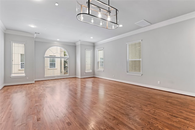 unfurnished living room featuring visible vents, baseboards, wood finished floors, and ornamental molding