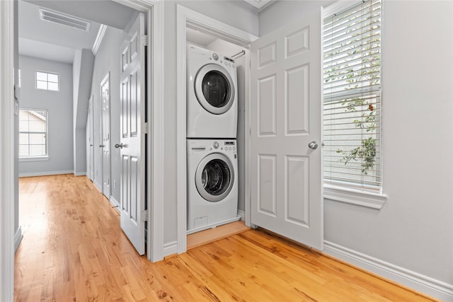 washroom with baseboards, visible vents, laundry area, stacked washer and dryer, and light wood-type flooring