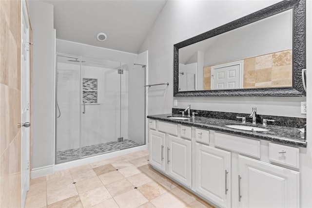 full bath featuring a sink, lofted ceiling, double vanity, and a shower stall