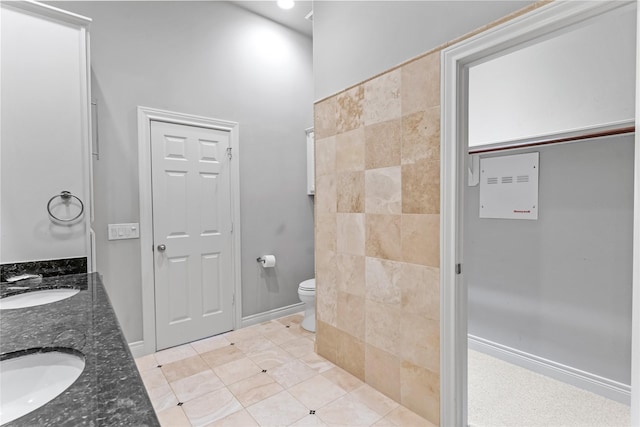 full bathroom featuring a sink, baseboards, toilet, and double vanity