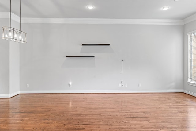 spare room featuring a notable chandelier, ornamental molding, wood finished floors, recessed lighting, and baseboards