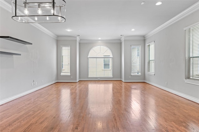 unfurnished living room with crown molding, wood finished floors, and baseboards