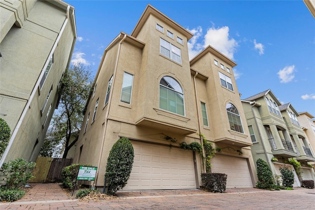 townhome / multi-family property featuring stucco siding, a garage, driveway, and fence