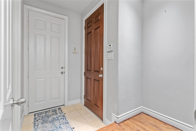 foyer entrance with light tile patterned flooring and baseboards