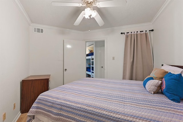 bedroom with ornamental molding, visible vents, and a textured ceiling