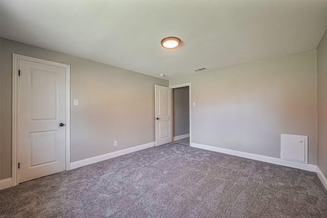 unfurnished room with carpet, visible vents, and baseboards