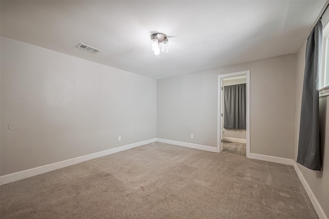 carpeted empty room with visible vents and baseboards