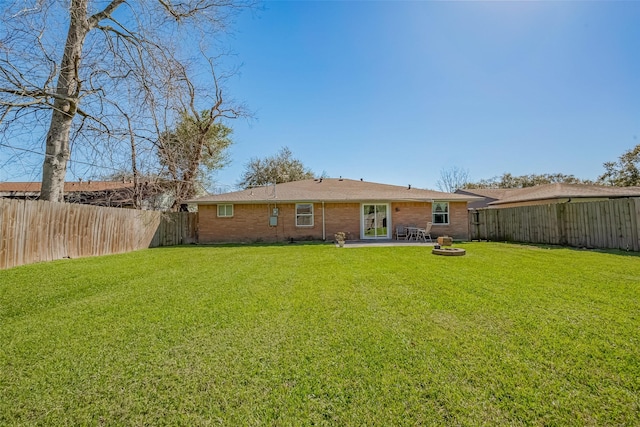 back of property with a patio area, a fenced backyard, a yard, and brick siding