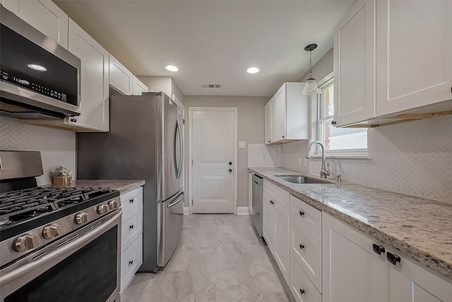 kitchen with stainless steel appliances, visible vents, white cabinetry, a sink, and light stone countertops