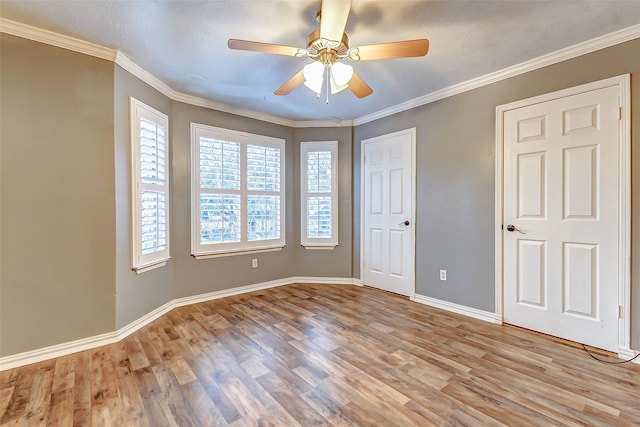 spare room with baseboards, wood finished floors, a ceiling fan, and crown molding