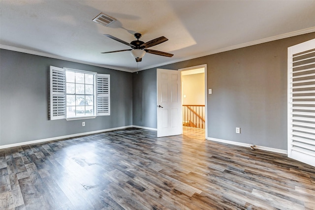 empty room with ornamental molding, visible vents, baseboards, and wood finished floors