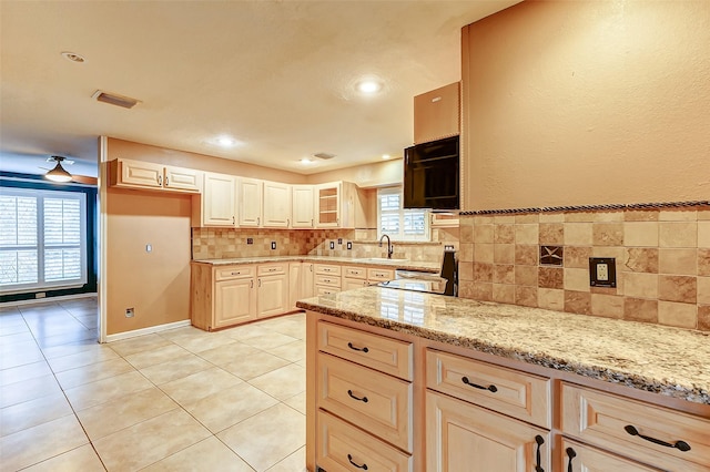 kitchen with light stone counters, backsplash, a sink, and light tile patterned flooring