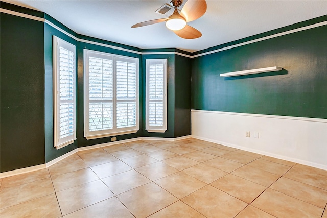 tiled spare room featuring ceiling fan, crown molding, and baseboards