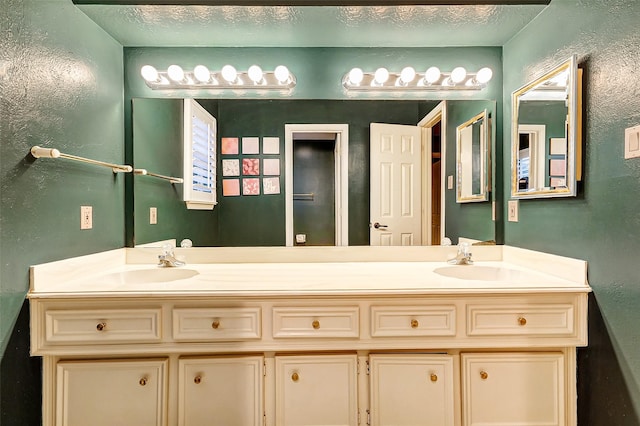 full bathroom with a textured wall, double vanity, and a sink