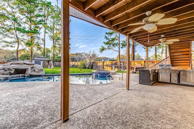 view of patio / terrace with an outdoor structure, an outdoor kitchen, a fenced backyard, and a ceiling fan