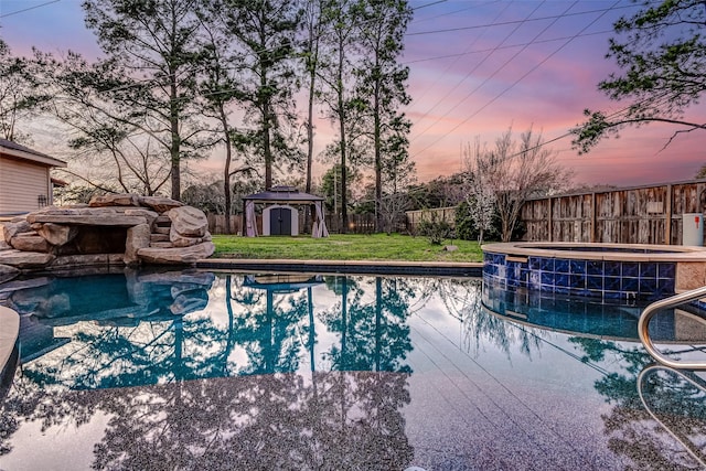 view of swimming pool with an outbuilding, an in ground hot tub, a fenced backyard, and a fenced in pool