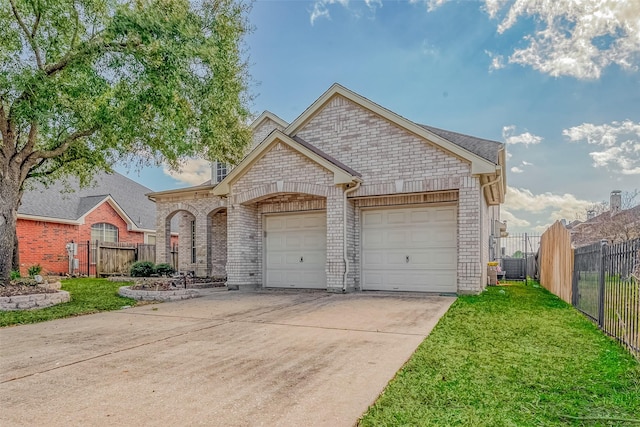 view of front facade with driveway, fence, a front yard, an attached garage, and brick siding