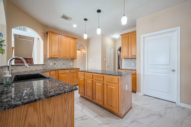 kitchen with visible vents, arched walkways, marble finish floor, and a sink