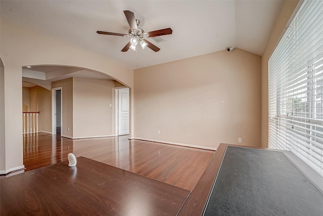 spare room with wood finished floors, visible vents, arched walkways, ceiling fan, and vaulted ceiling