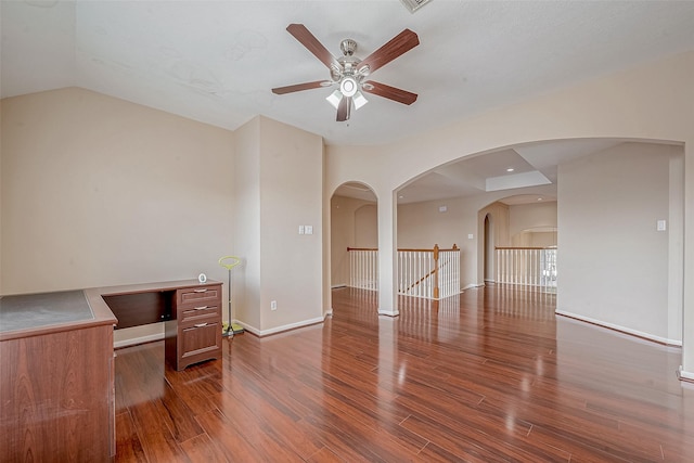 interior space featuring arched walkways, baseboards, ceiling fan, and wood finished floors