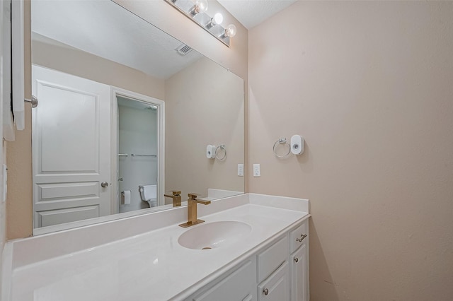 bathroom featuring visible vents, toilet, and vanity