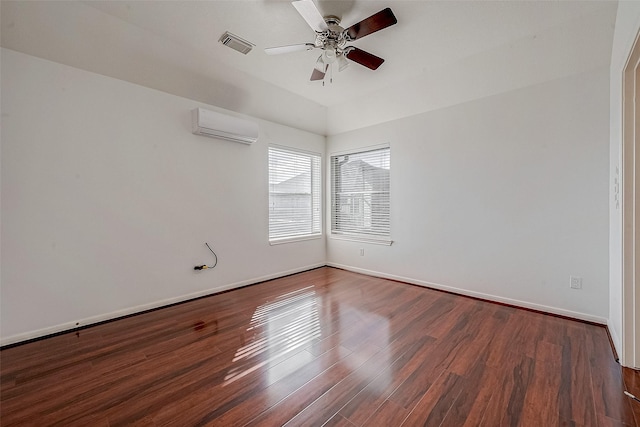 empty room featuring visible vents, a wall mounted AC, dark wood finished floors, baseboards, and ceiling fan